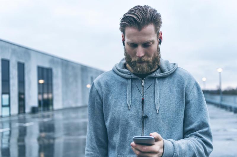 Hombre con barba usando en la calle un móvil