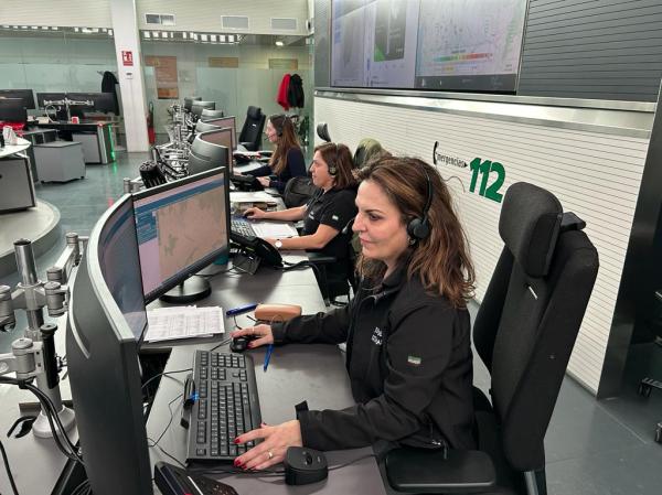 Dos trabajadoras del 112 con una ordenador y unos cascos atendiendo llamadas sentadas